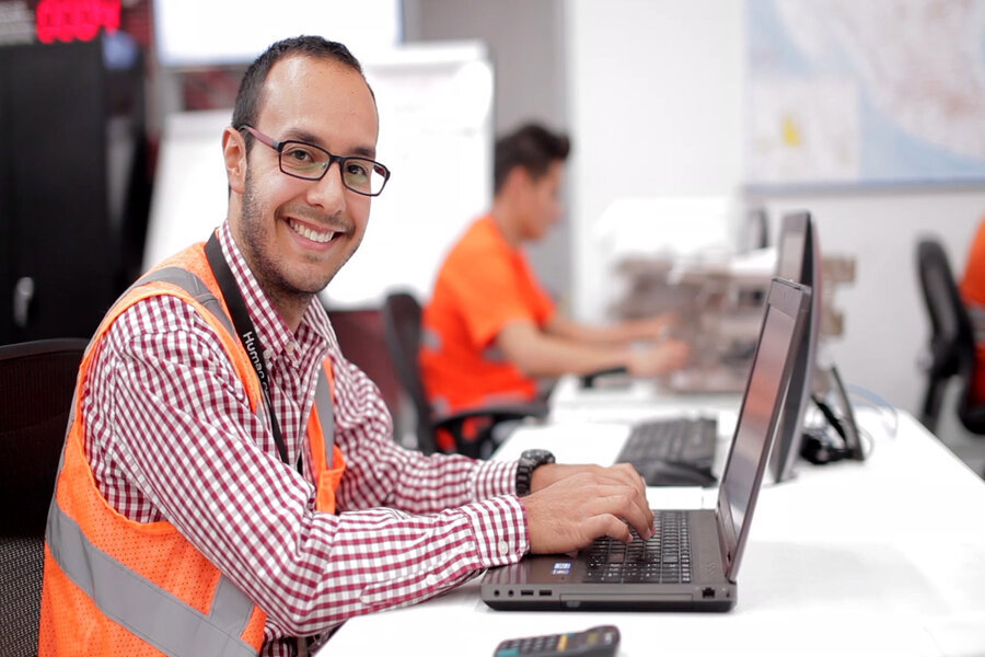 smiling employee siting at a desk with laptop